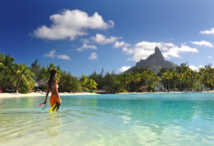 Woman getting into the innerlagoon with snorkeling material at the hotel Le Meridien Bora Bora facing the Otemanu mount