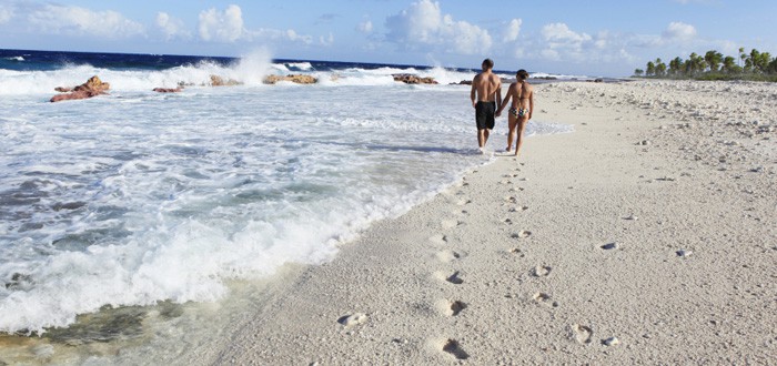Couple walking on a beach of Mangareva island